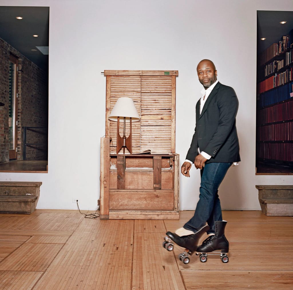 Art Basel Awards 2026 — Theaster Gates stojí v priestore na chicagskom South Side vedľa dreveného nábytku a knižnice, 2014.