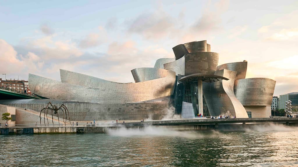 Múzeum Guggenheim Bilbao od Franka Gehryho, pohľad od rieky Nervión s odrazom titanovej fasády vo vode