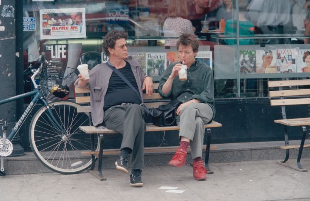 Art Basel Awards 2026 — Laurie Anderson a Lou Reed sedia na lavičke pred novinovým stánkom v New Yorku.