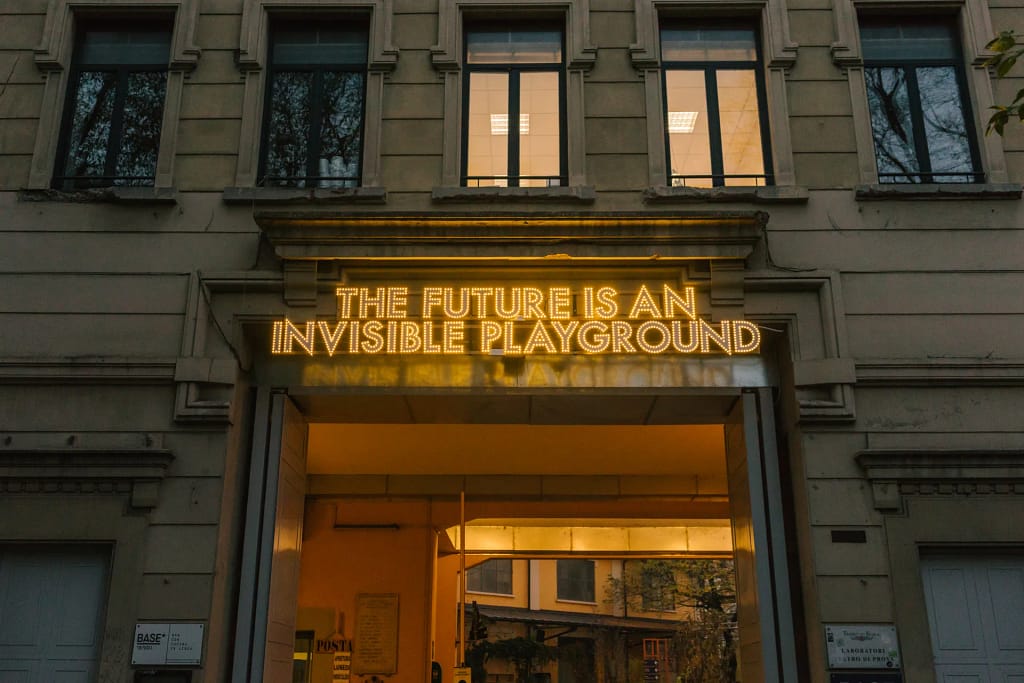 BASE Milano – neonový nápis The Future is an Invisible Playground nad vstupom do bývalého priemyselného komplexu Ansaldo, Miláno.