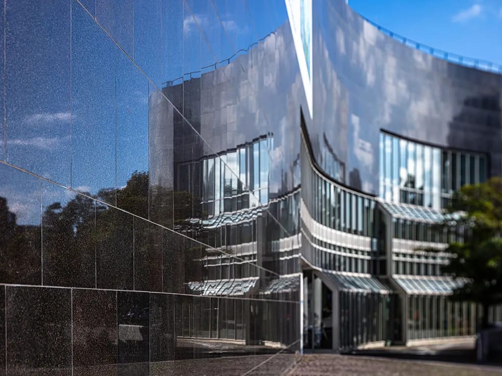 Architektonický pohľad na čiernu žulovú fasádu K20 Kunstsammlung Nordrhein-Westfalen v Düsseldorfe s odrazmi okolitých budov