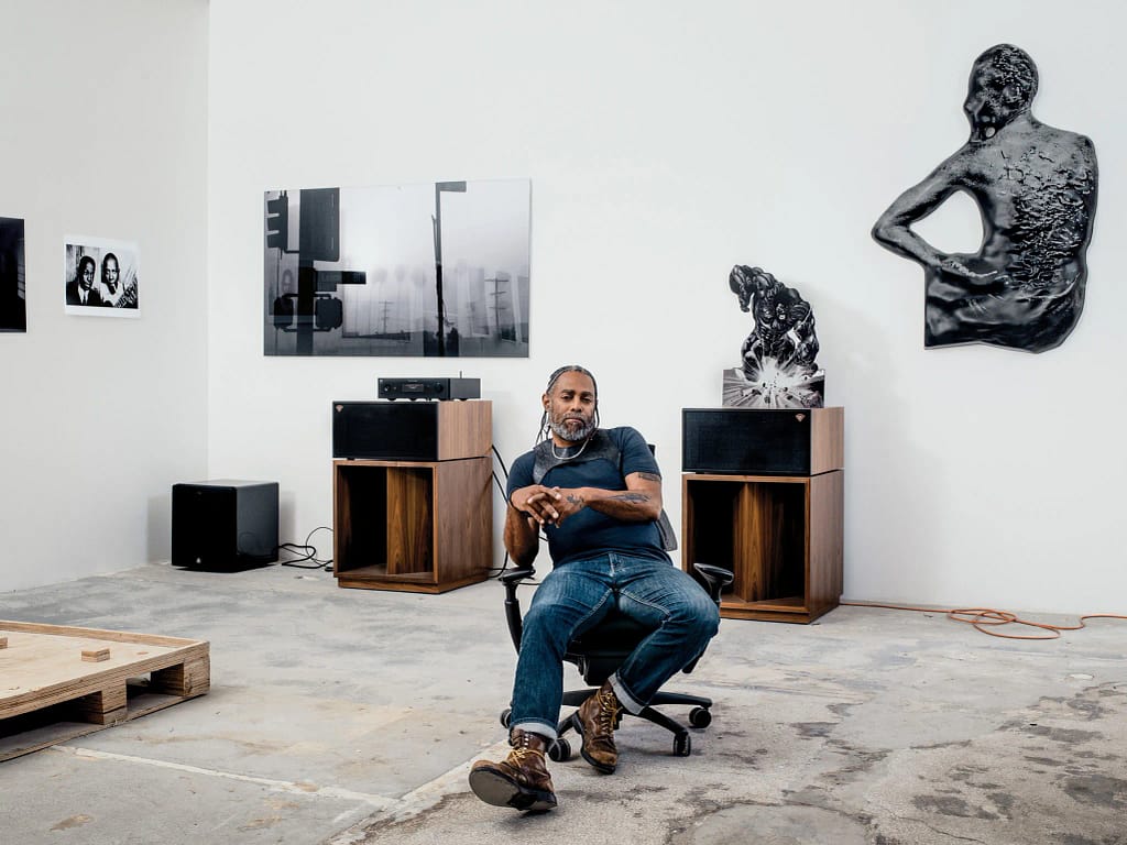 Art Basel Awards 2026 — Arthur Jafa sedí v ateliéri obklopený svojimi dielami, vrátane sochy Ex-Slave Gordon 2017 a videa Love Is the Message.
