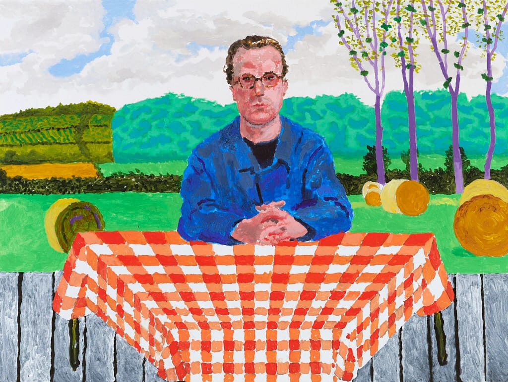 David Hockney, maľba muža sediaceho za oranžovo-bielym kockovaným obrusom s normandskou krajinou v pozadí, 2025
