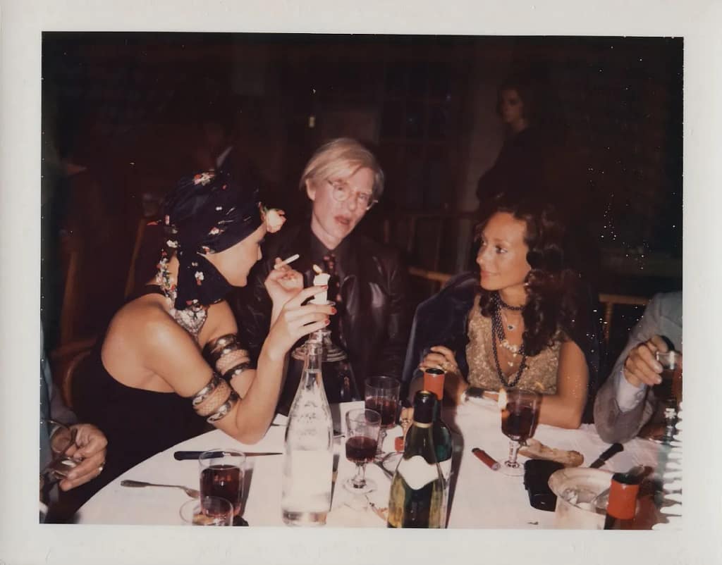 Saint Laurent Warhol — Loulou de la Falaise, Andy Warhol a Marisa Berenson pri večeri, 1972, farebná fotografia.