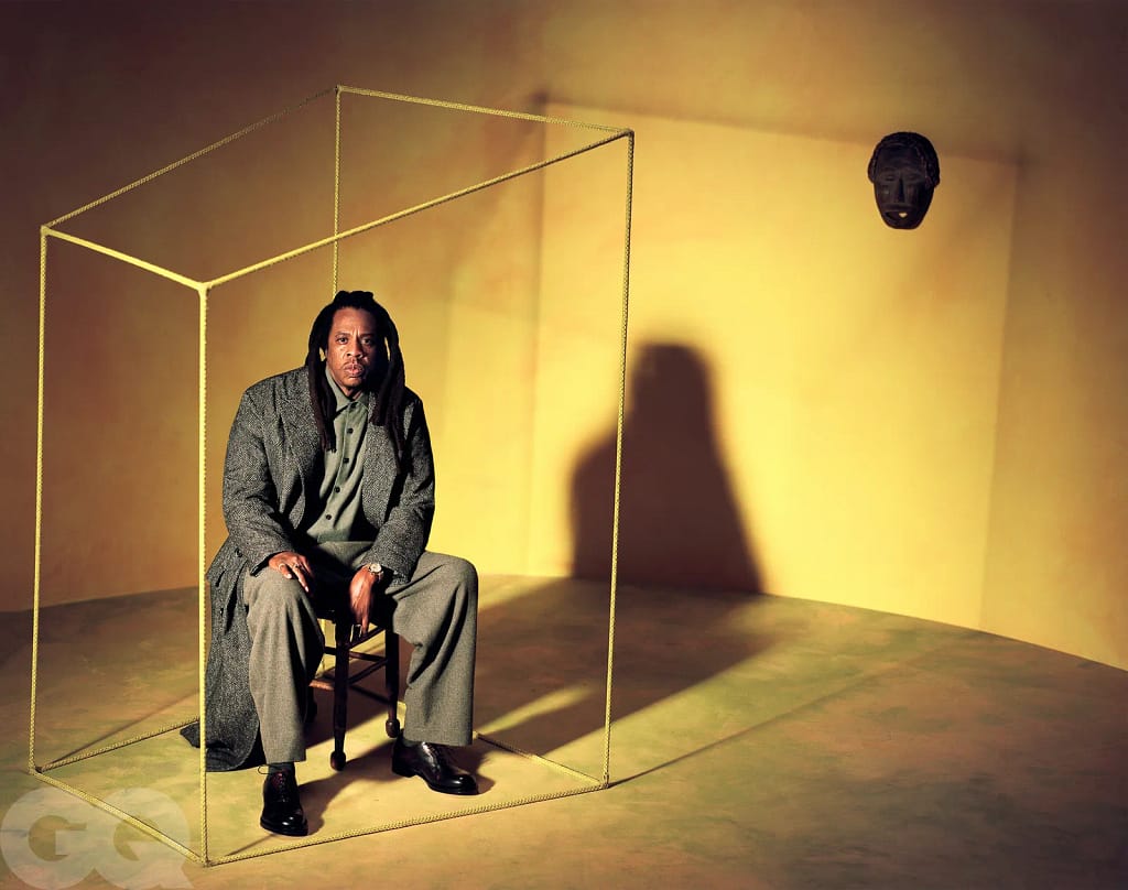 JAŸ-Z sedí na stoličke obklopený lanom v zlatom priestore, GQ globálne vydanie apríl 2026, foto Rashid Johnson