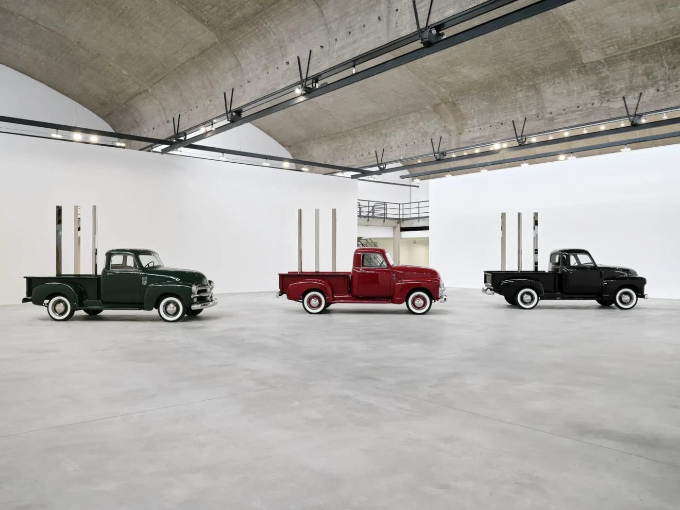 Tri vintage nákladiaky Chevrolet z roku 1950 v zelené, červenej a čiernej farbe s geometrickými tyčami na korbe, inštalačný pohľad, Gagosian Le Bourget, Paríž