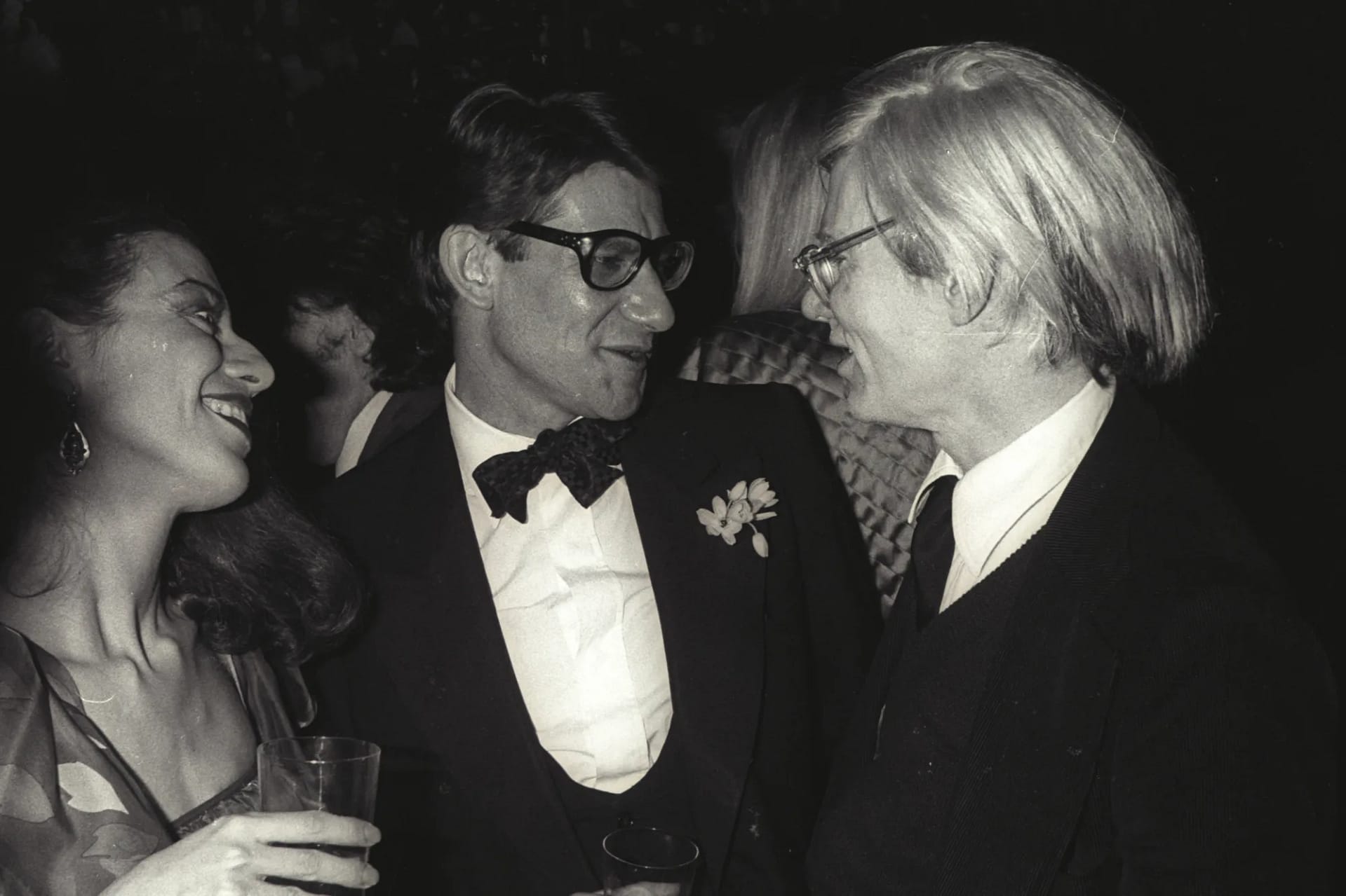 Saint Laurent Warhol — Yves Saint Laurent a Andy Warhol na párty v Paríži 1979, čiernobiela fotografia, v pozadí Warholov portrét Saint Laurenta 1972.