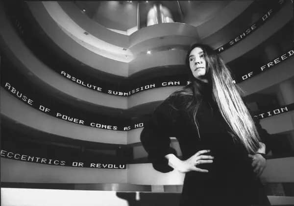 Art Basel Awards 2026 — Jenny Holzer stojí pred LED inštaláciou Untitled v Guggenheim Museum New York 1990, čiernobiela fotografia.