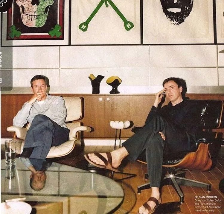 Dries Van Noten a Raf Simons sedia v súkromnom interiéri v Antverpách, klasické Eames lounge stoličky, Mike Kelley obrazy a Pol Chambost vázy.
