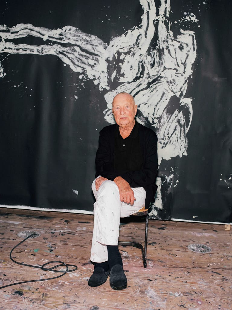 Georg Baselitz sedí na stoličke v ateliéri Ammersee 2021 pred čiernobielou maľbou na stene foto Christoph Schaller