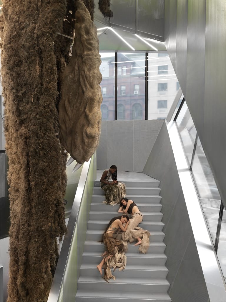 New Museum 2026, Klára Hosnedlová, Shelter, 2026 — monumentálna organická socha z ľanu a kameňa v atriovej schodnici New Museum, s performermi v popredí.