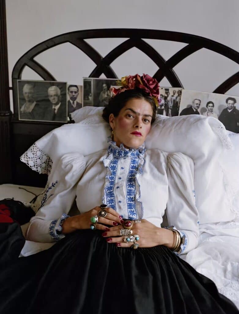 Tracey Emin pózuje ako Frida Kahlo v posteli s kvetinovou korunou, biela vyšívaná blúzka, čierna sukňa, fotografia Mary McCartney 2000