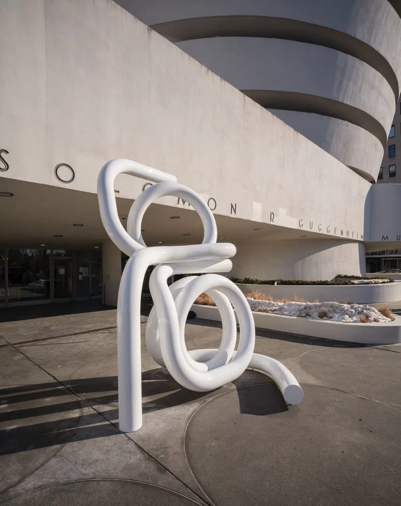 Biela abstraktná skulptúra Carol Bove z prepletených trubiek pred fasádou Guggenheim Museum v New Yorku, 2026